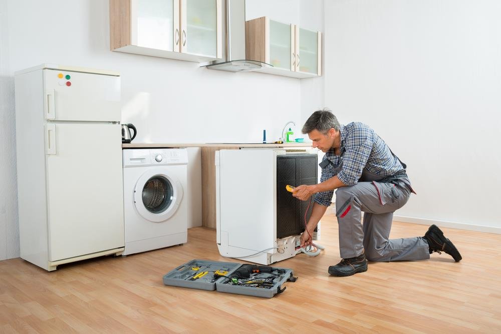 Appliance engineer repairing a refrigerator in a home
